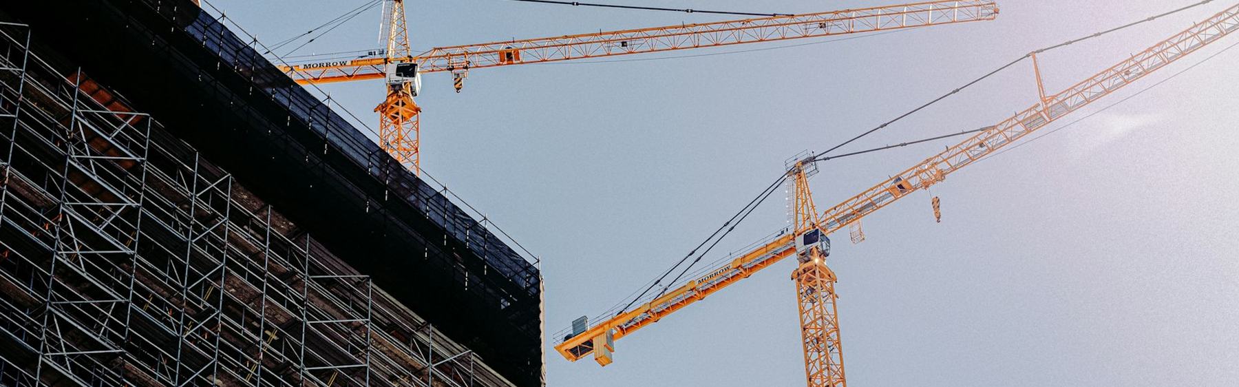 Tower cranes working above a scaffolded commercial building