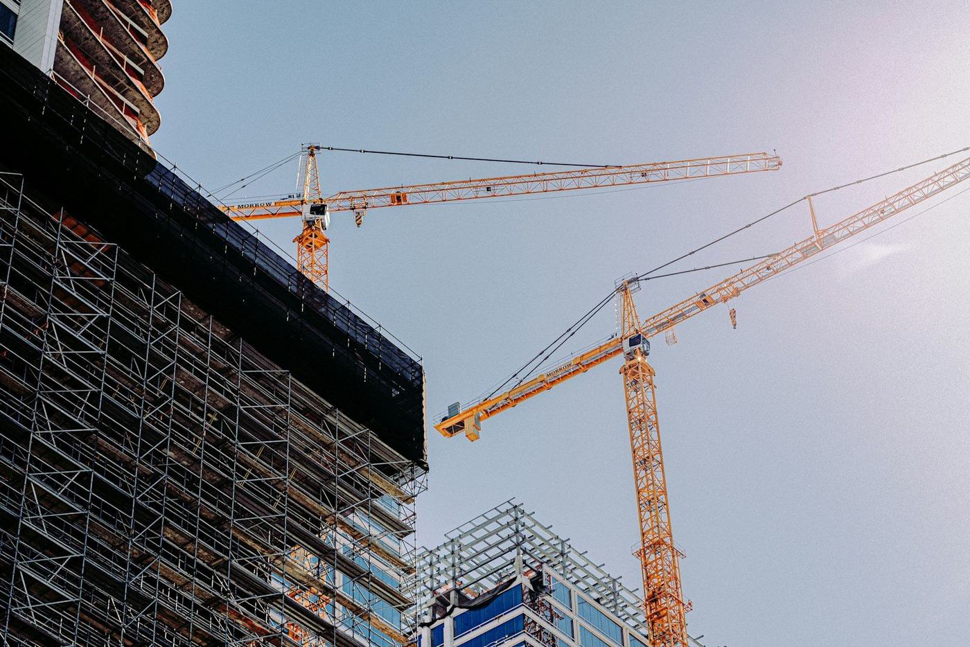Glass-fronted commercial tower under construction with tower cranes