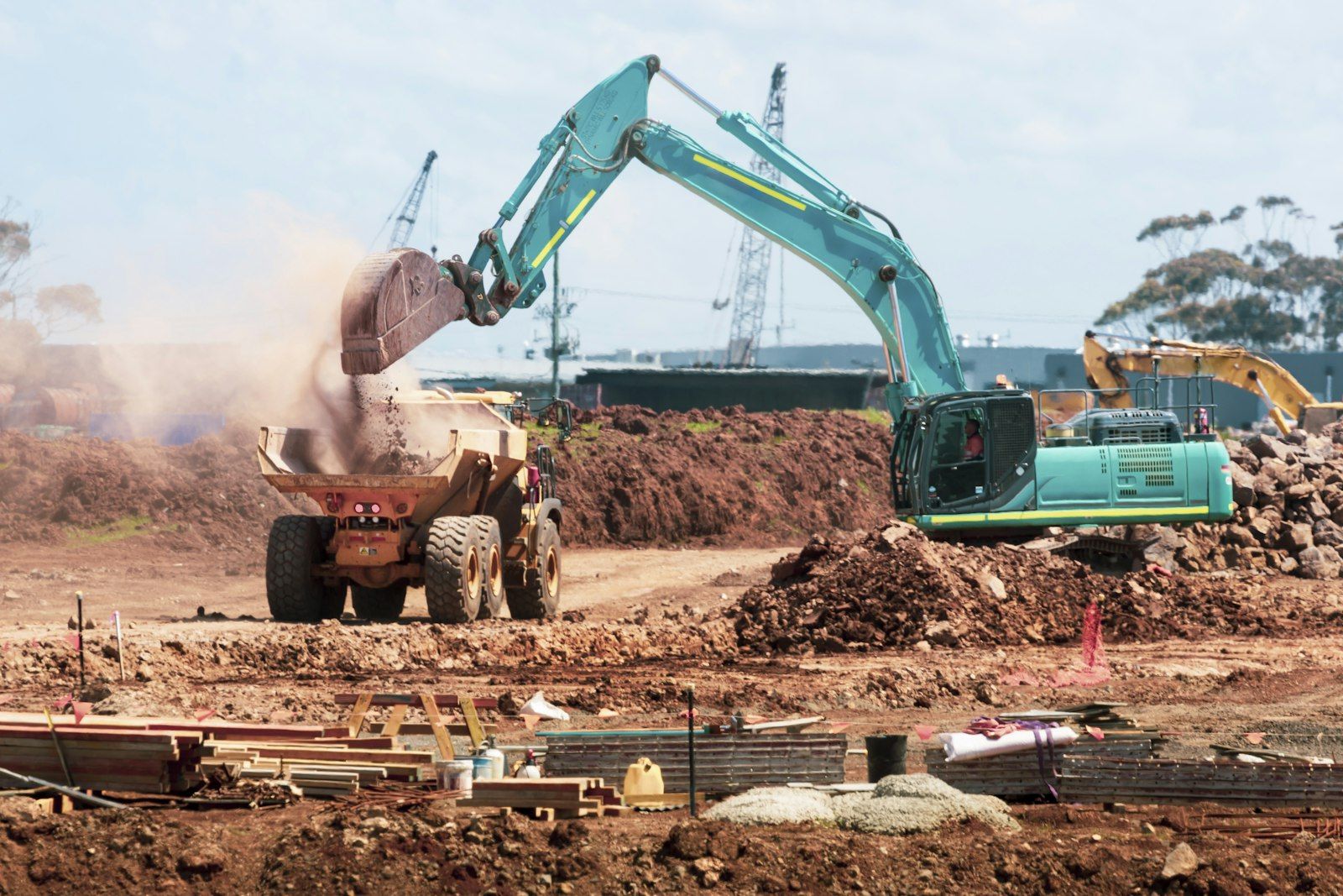 Excavator loading spoil into an articulated dump truck on a construction site