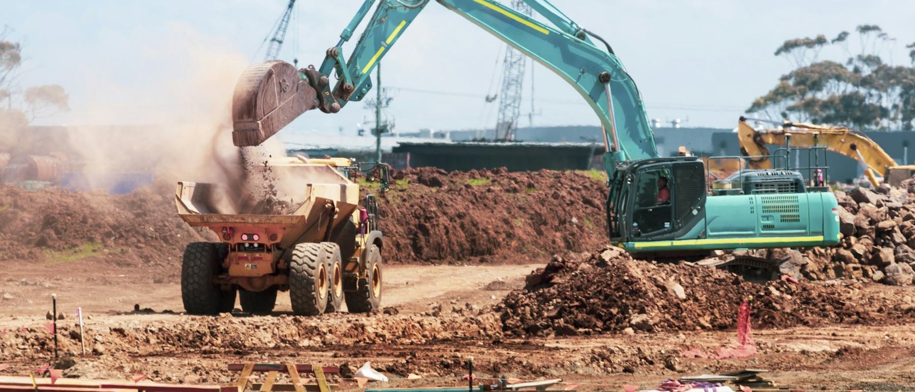 Excavator loading spoil into an articulated dump truck